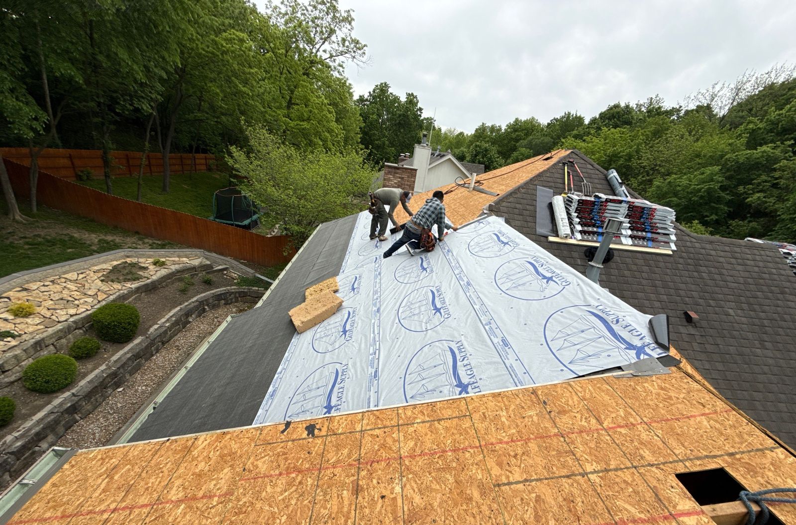 Crew installing underlayment over roof decking
